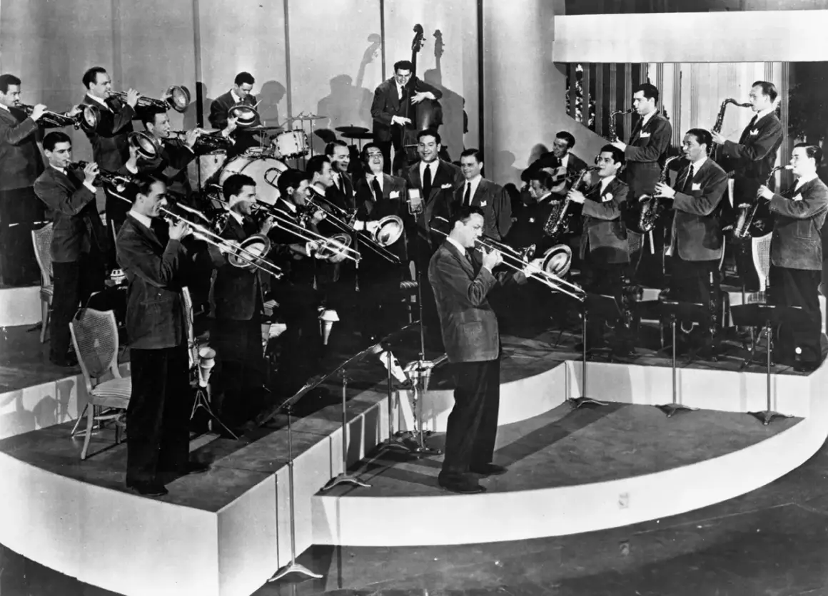 Una big band de jazz en pleno concierto, con músicos tocando trompetas, trombones, saxofones y contrabajo. ¡Pura energía musical!