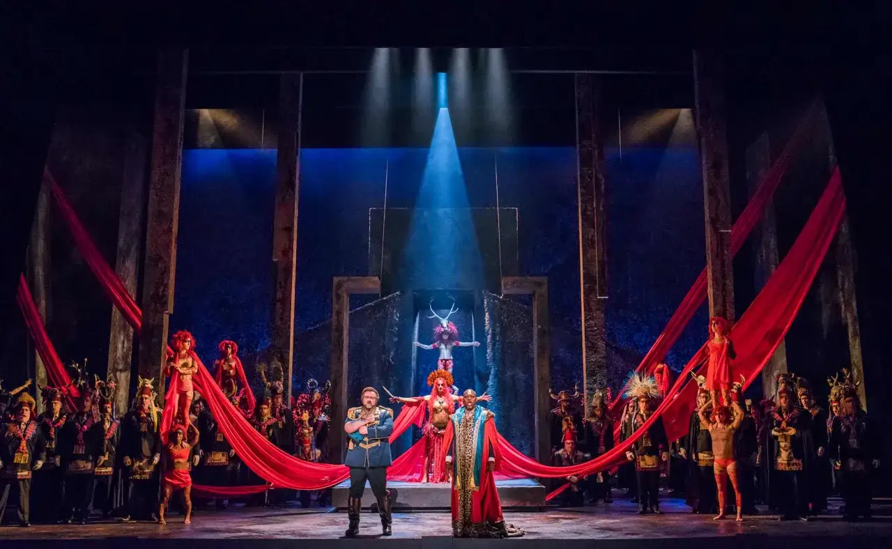 Escena dramática de óperas de Verdi con vestuarios coloridos y telas rojas ondeantes.