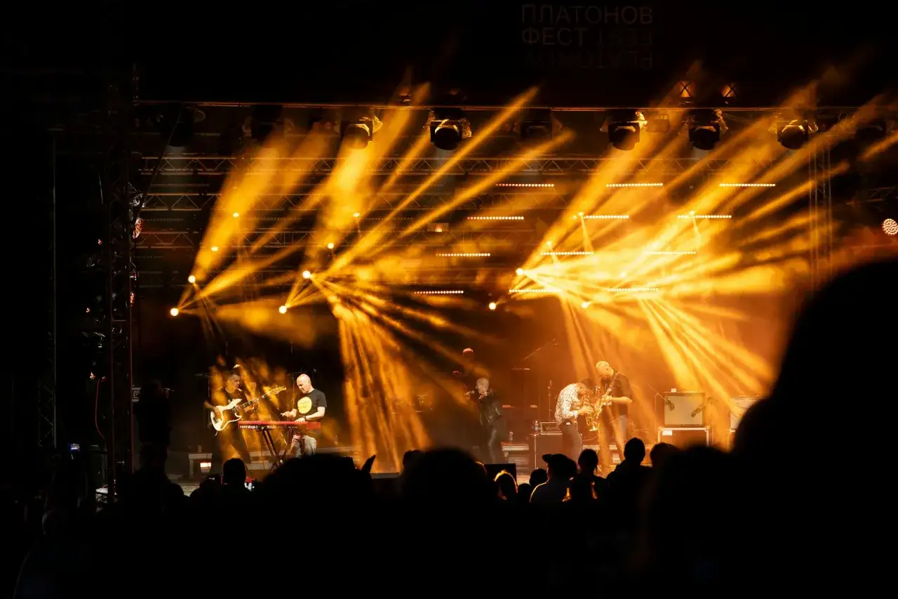 Banda en vivo bajo luces doradas, un concierto que ilumina la industria musical.