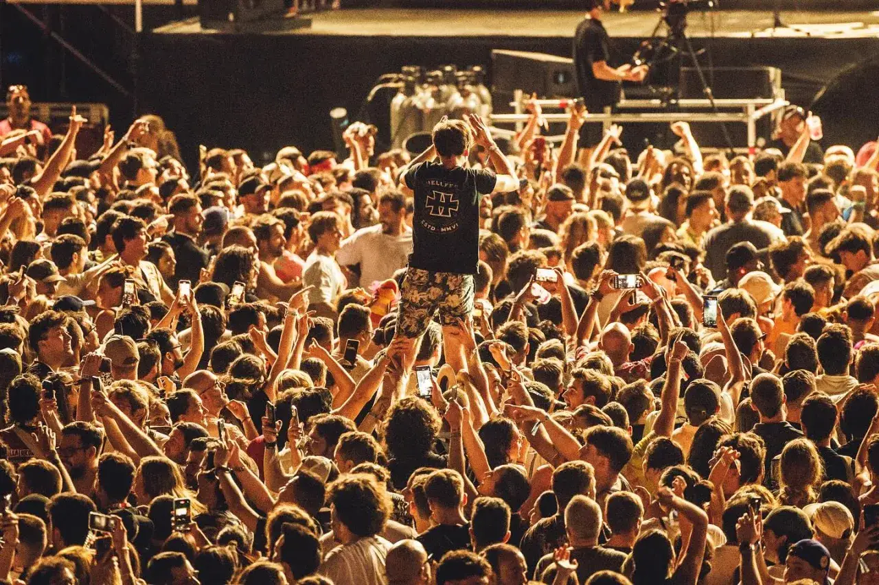 Multitud en un concierto, un hombre se alza sobre los hombros de otros, capturando la esencia de que es la rave.