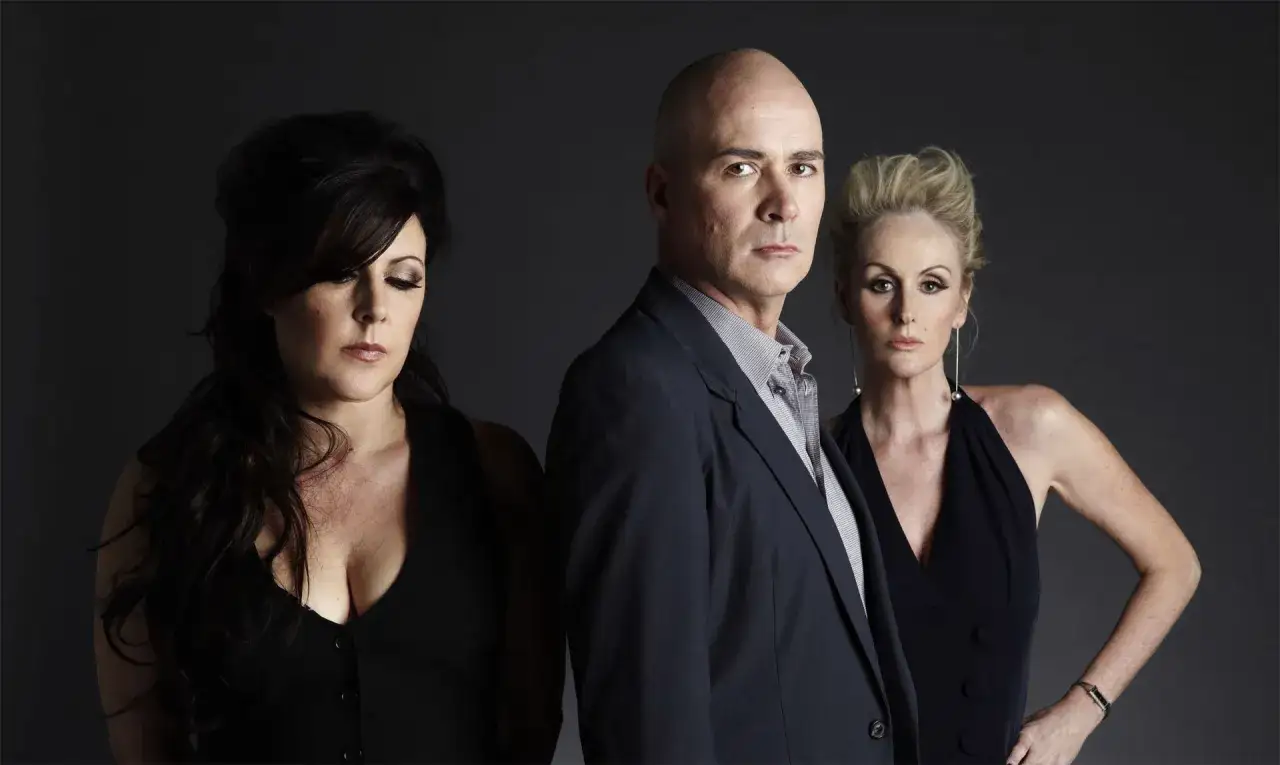 Miembros de The Human League: Philip Oakey, Joanne Catherall y Susan Ann Sulley posan con miradas intensas.