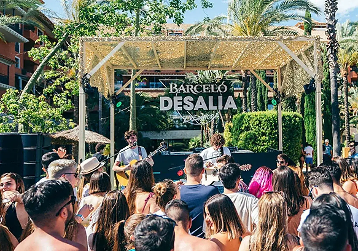 Un concierto en Desalia, un festival de m&uacute;sica al aire libre con palmeras y un escenario.