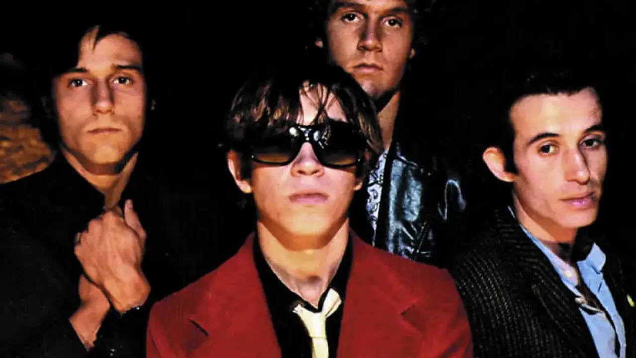 Cuatro hombres con estilo, evocando la energ&iacute;a de la new wave music, posan para una foto.