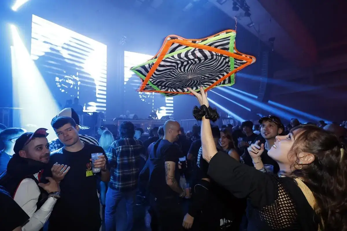 Gente disfrutando en el wake up festival, una mujer levanta un objeto con dise&ntilde;o psicod&eacute;lico.
