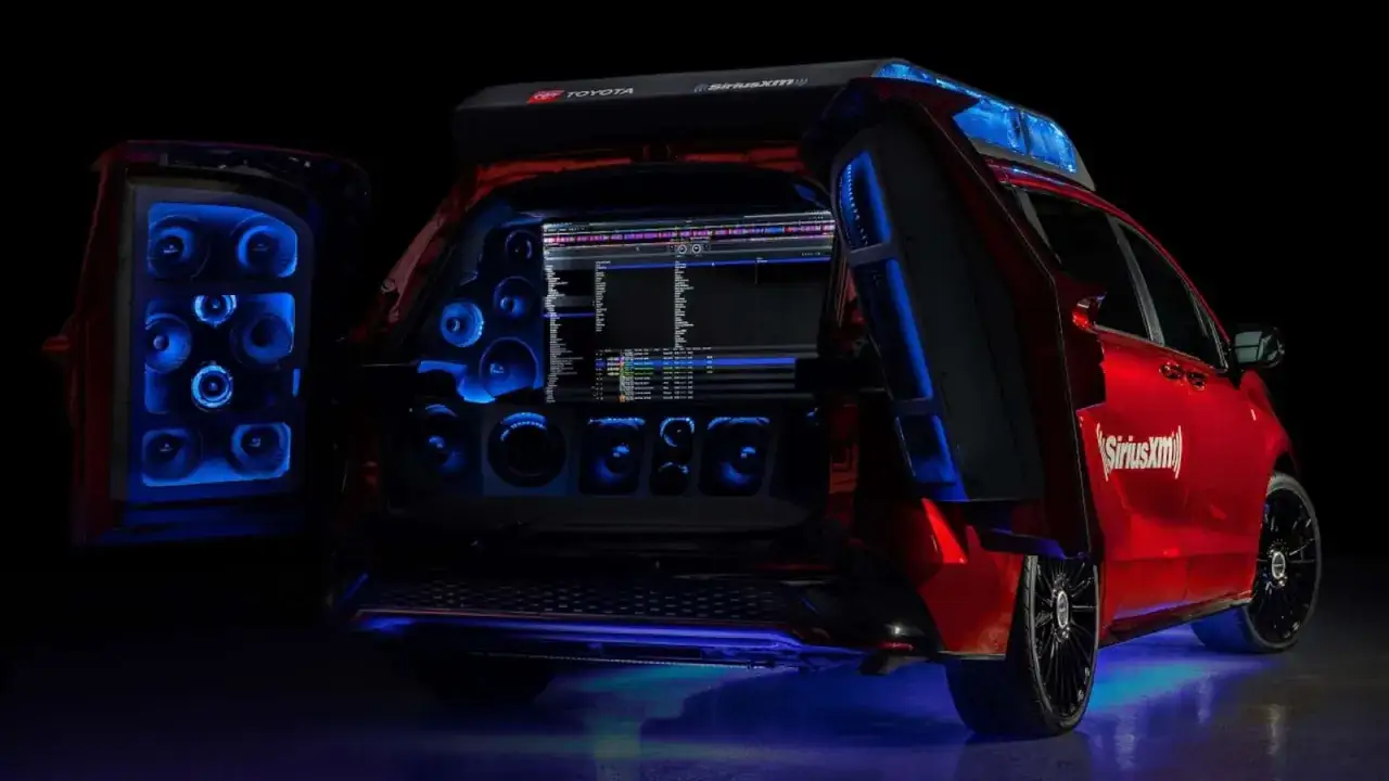 Un coche rojo con puertas traseras abiertas, mostrando un sistema de sonido con luces azules y una pantalla de DJ. &iexcl;Esto es parkineo que es!