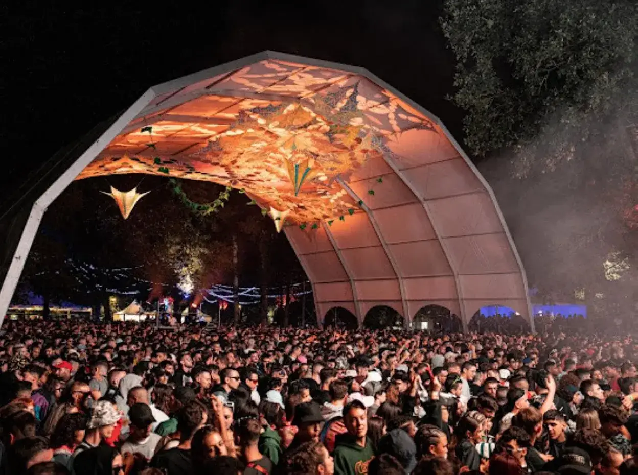 Multitud disfrutando bajo una carpa iluminada en un festival. ¡No te pierdas las próximas aquasella fechas!