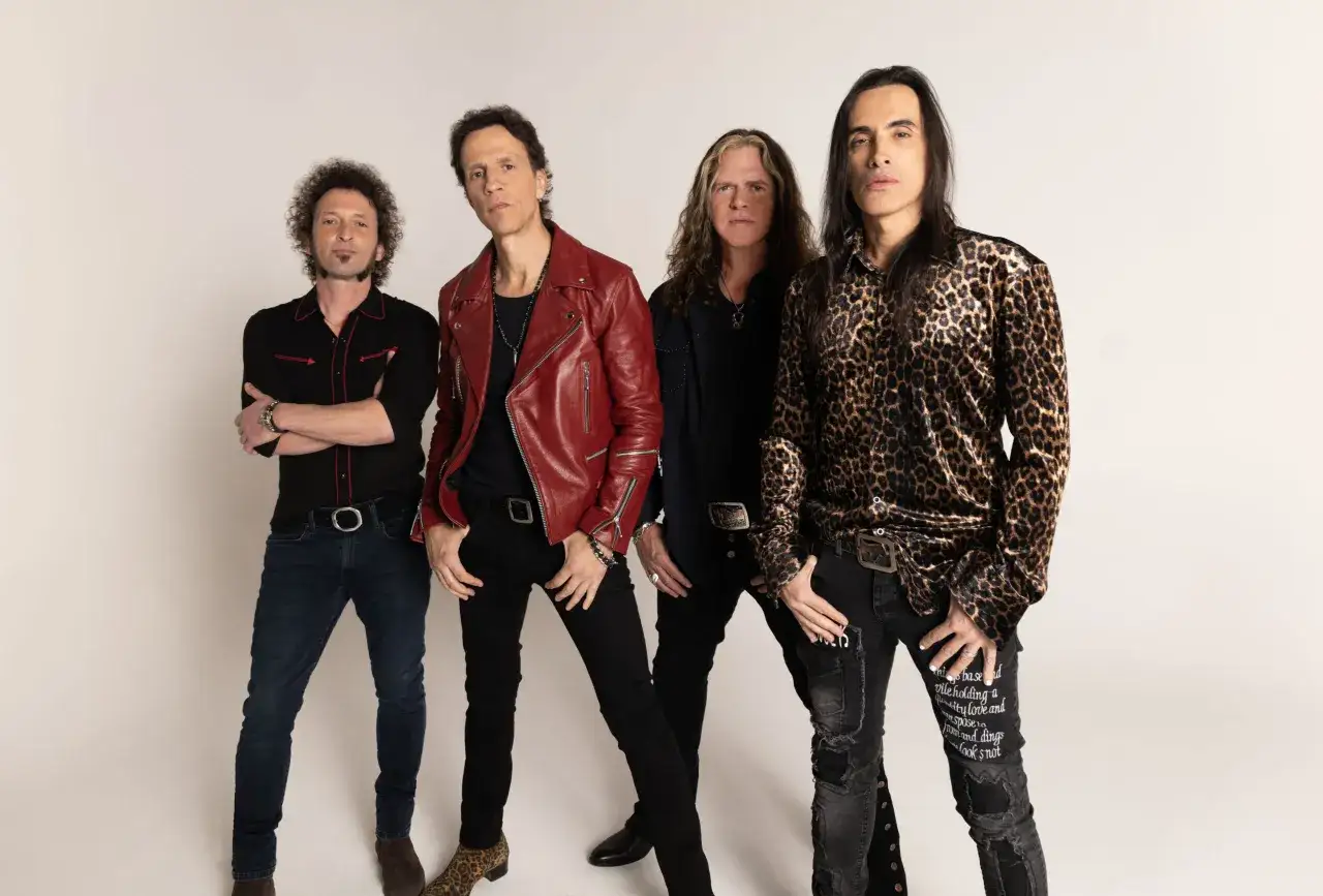 Los miembros de Extreme posan con estilo: uno con chaqueta de cuero roja, otro con estampado de leopardo y los otros dos con atuendos oscuros.