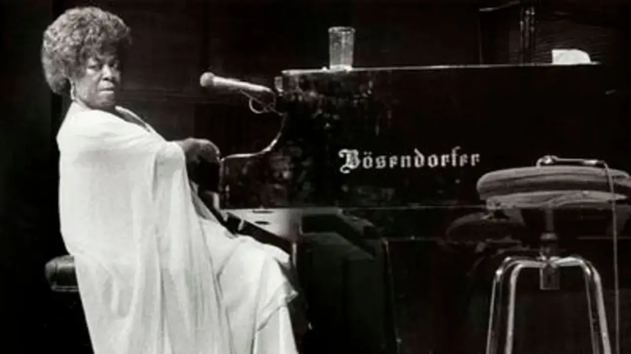 Dinah Washington, con su ic&oacute;nico peinado afro, sentada al piano B&ouml;sendorfer, lista para ofrecer una actuaci&oacute;n inolvidable.