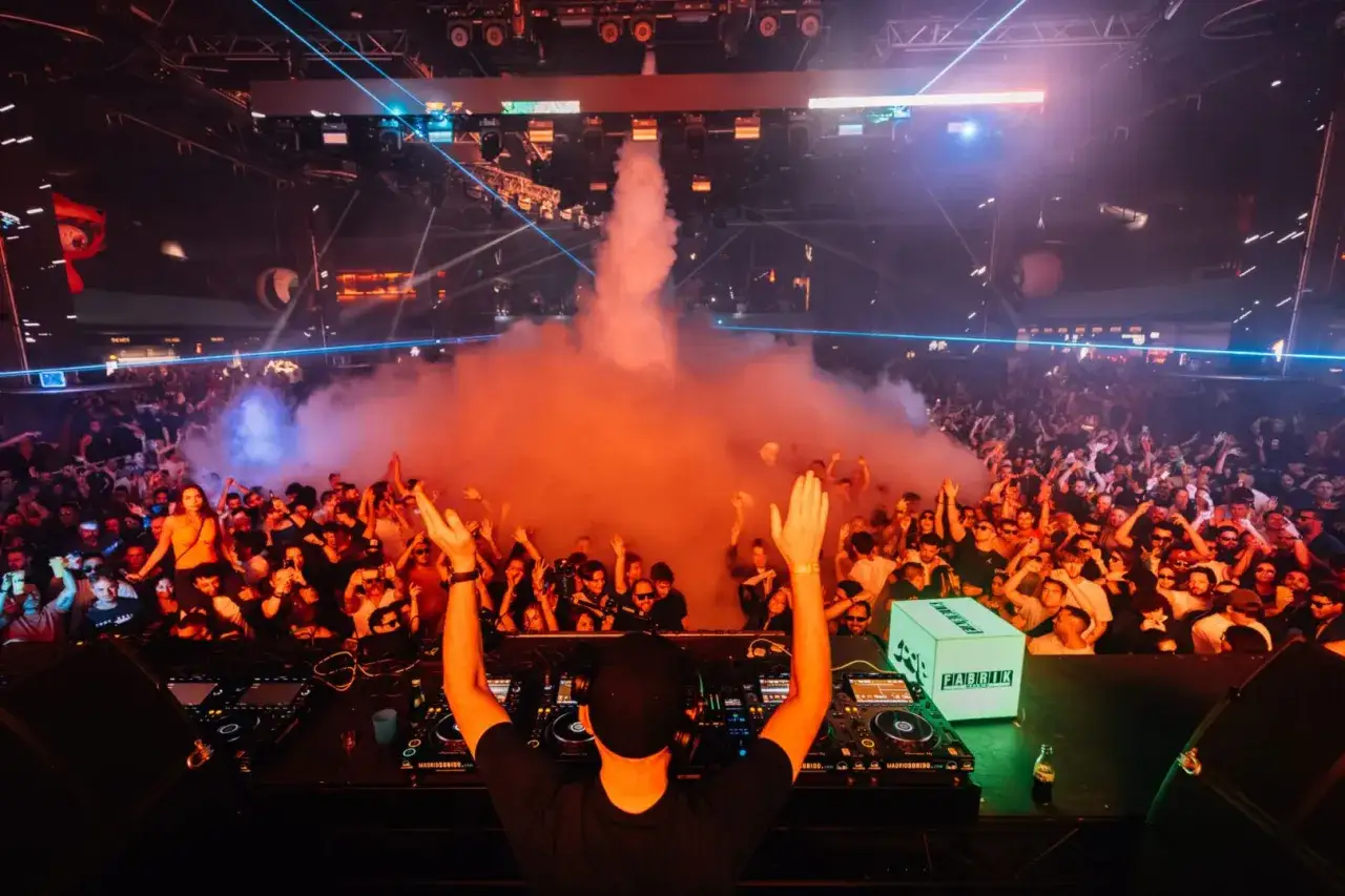 La multitud enloquece con humo naranja y luces láser mientras el DJ pincha en Fabrik, Madrid. ¡Una noche épica con Eric Prydz Madrid!