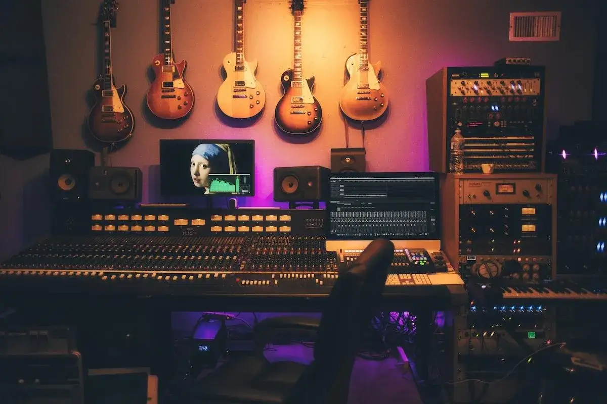 Estudio de grabación con guitarras colgadas, mesa de mezclas, monitores y equipo de audio. Un lugar ideal para crear música y sellos discograficos.