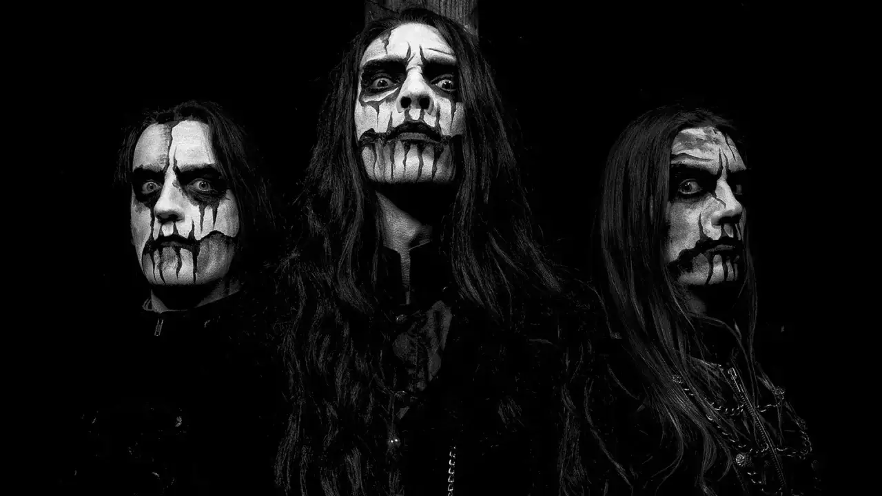 Tres m&uacute;sicos con maquillaje de corpse paint, caracter&iacute;stico de los grupos black metal, miran fijamente a la c&aacute;mara.