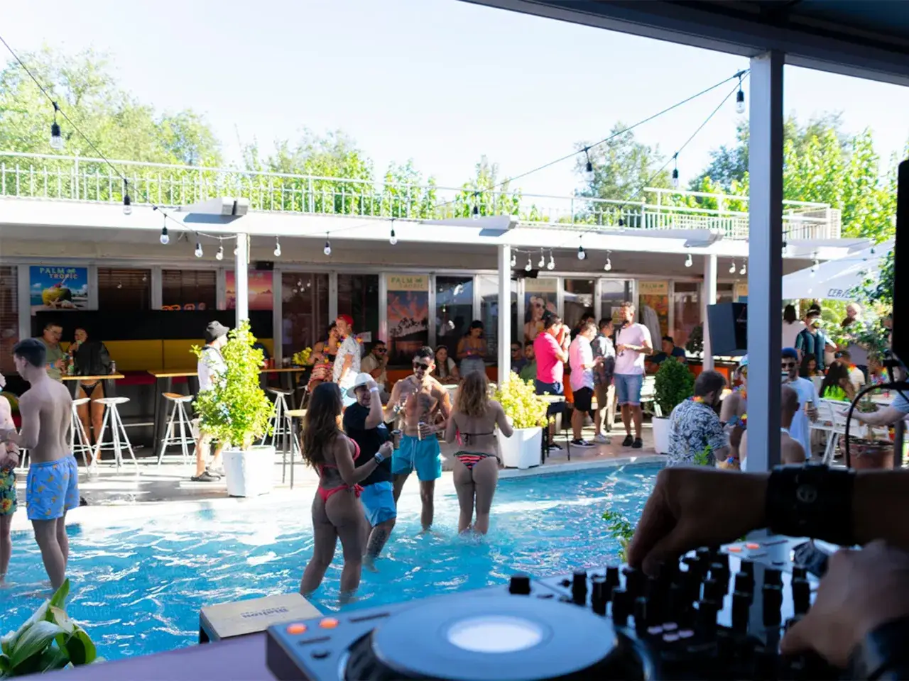 Gente disfrutando de un tardeo techno en Madrid, bailando y refresc&aacute;ndose en una piscina.