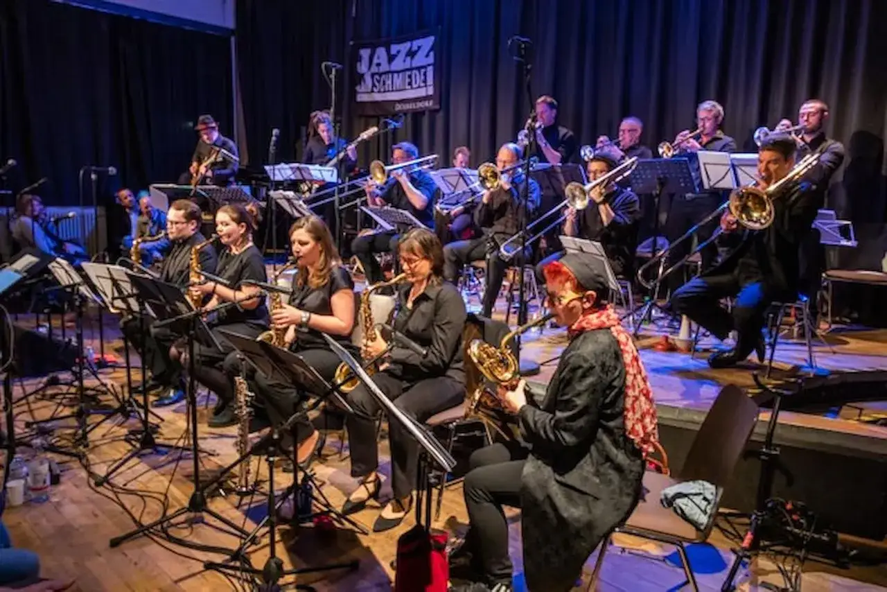 Una big band de jazz en plena actuación, con músicos tocando saxofones, trompetas y trombones.