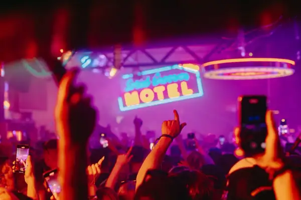 Gente bailando bajo el letrero de neón "Solid Grooves Ibiza Motel" en una fiesta vibrante.