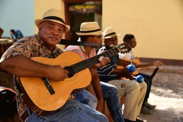 Son cubano cantantes, con guitarras y maracas, crean música alegre bajo el sol.