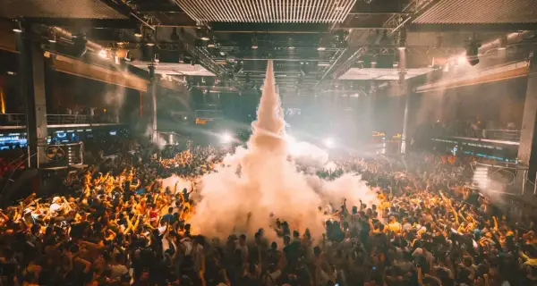 Multitud en un **tardeo techno Madrid**, con humo saliendo del centro y luces que iluminan la fiesta.
