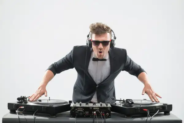 DJ con traje y auriculares, listo para mezclar. Aprende como entrar en una agencia de DJ y triunfar en la música.