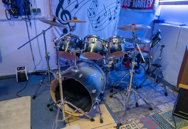 Batería de rock con platillos y un cartel de Bob Marley. ¿Te preguntas dnb que es? Es un género musical.