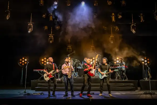 Cinco músicos en el escenario, con guitarras, bajo, saxofón y teclados. La banda, como si fueran hermanos, comparte sus opiniones musicales.