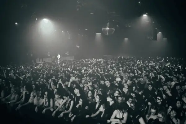 Multitud vibrante disfrutando de la techno musica en un club con luces tenues y una bola de discoteca giratoria.