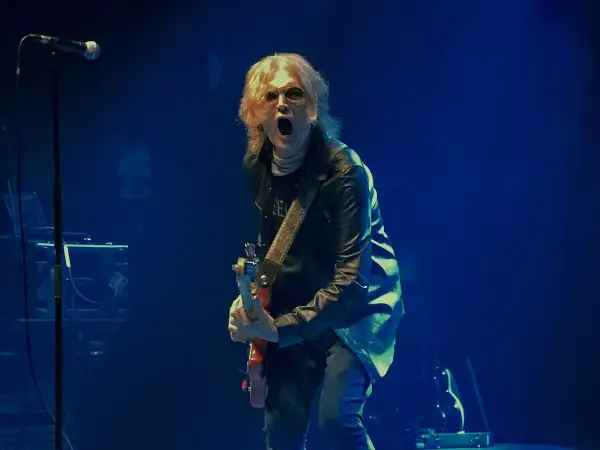 Glenn Hughes, con su banda, desata energía en el escenario. El vocalista y guitarrista, con su icónica melena rubia, grita al público mientras toca su instrumento.