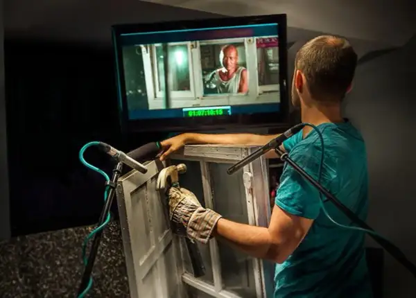 Un técnico de sonido crea efectos de **foley que es** el arte de añadir sonidos a una película, golpeando una ventana con un martillo.