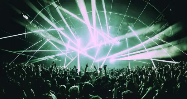 Una multitud celebra bajo un espectáculo de luces láser, un momento cumbre en la historia de la música electrónica.