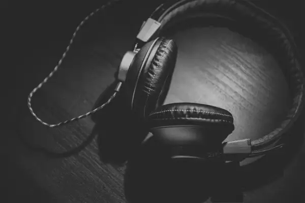 Auriculares negros sobre una superficie de madera, con un juego de luces y sombras que crea un efecto Haas.